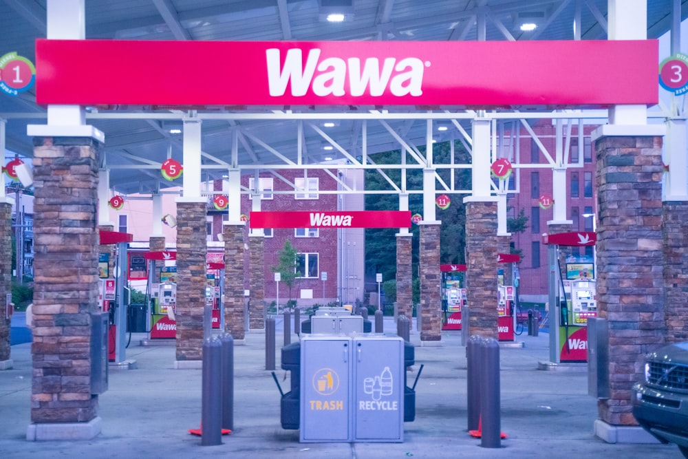 uma placa vermelha que diz wawa em frente a um posto de gasolina