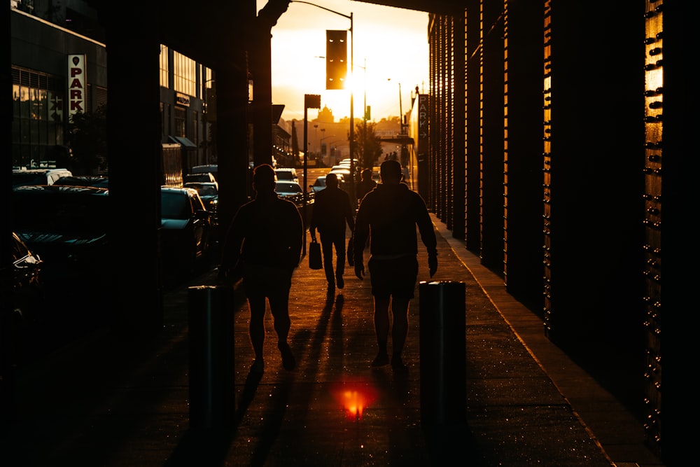 a group of people walking down a street at sunset