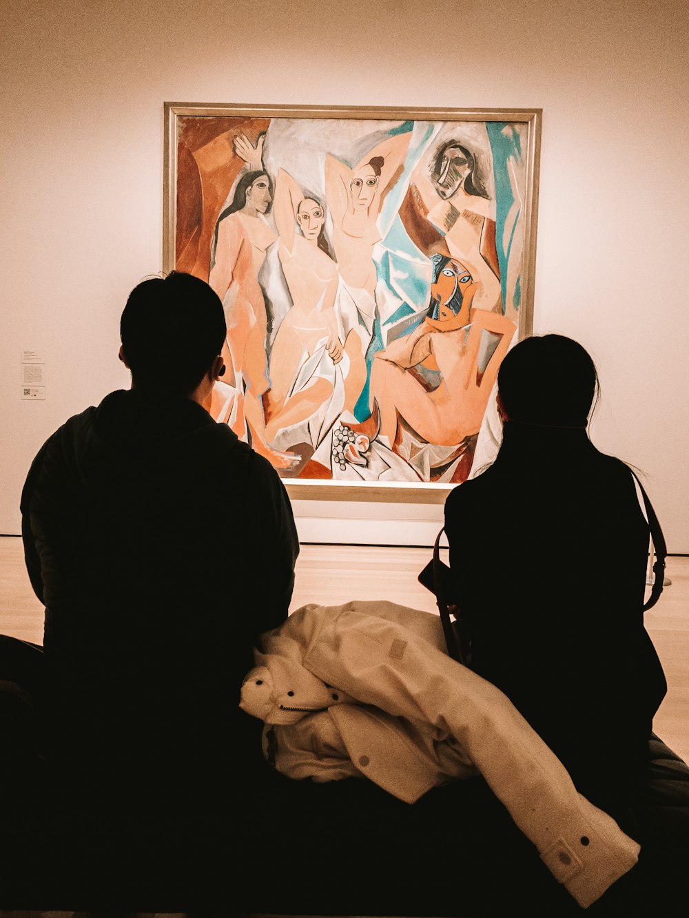 two people looking at a painting in a museum