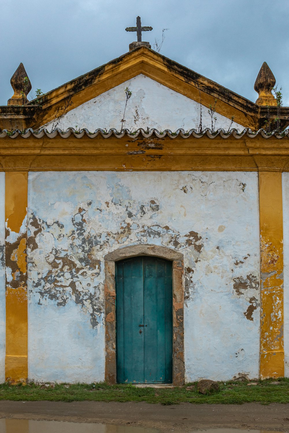 a church with a blue door and a cross on top of it