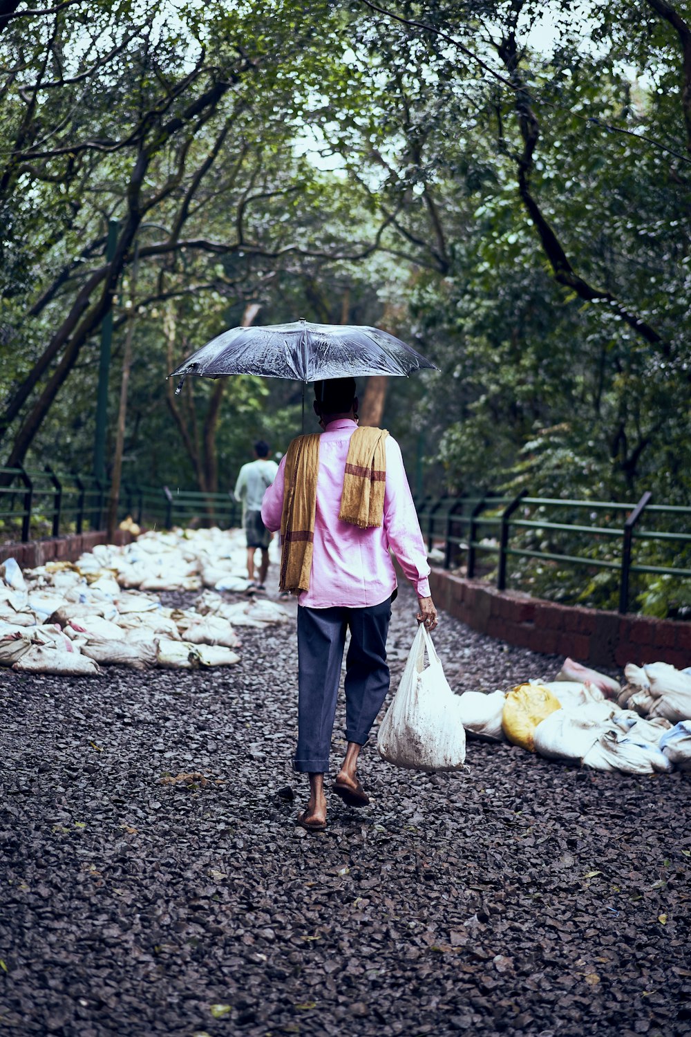 a woman walking down a path holding an umbrella