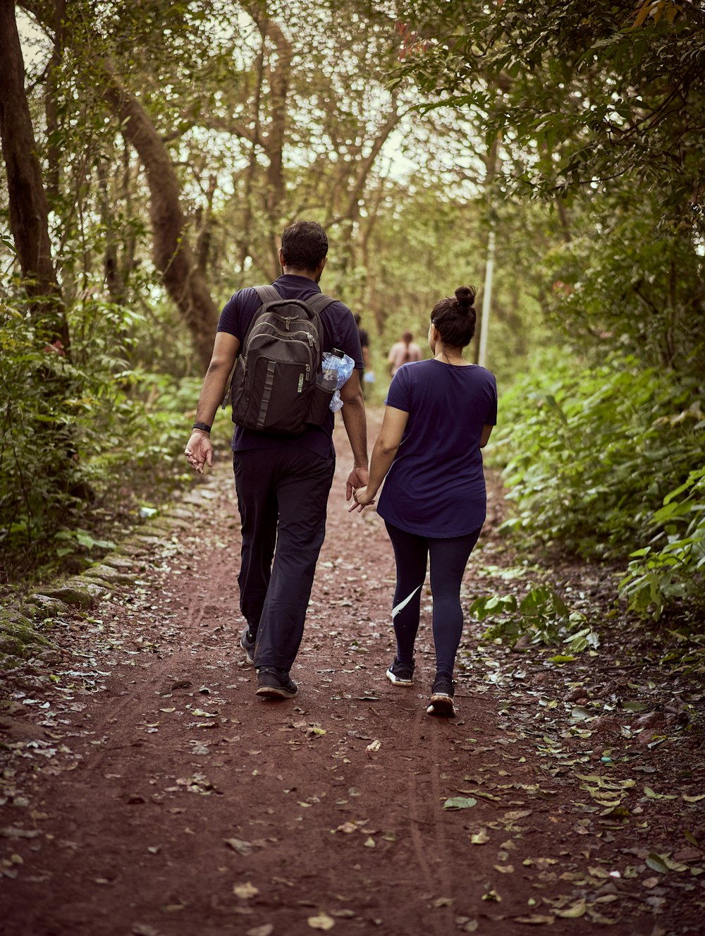 a couple of people walking down a dirt road