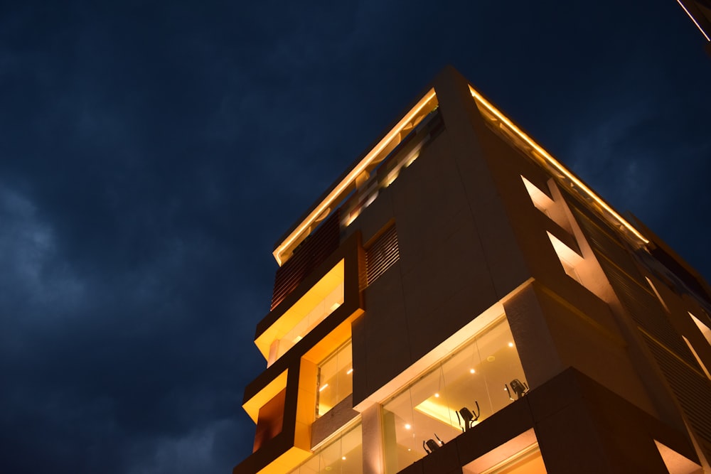 a tall building lit up at night under a cloudy sky