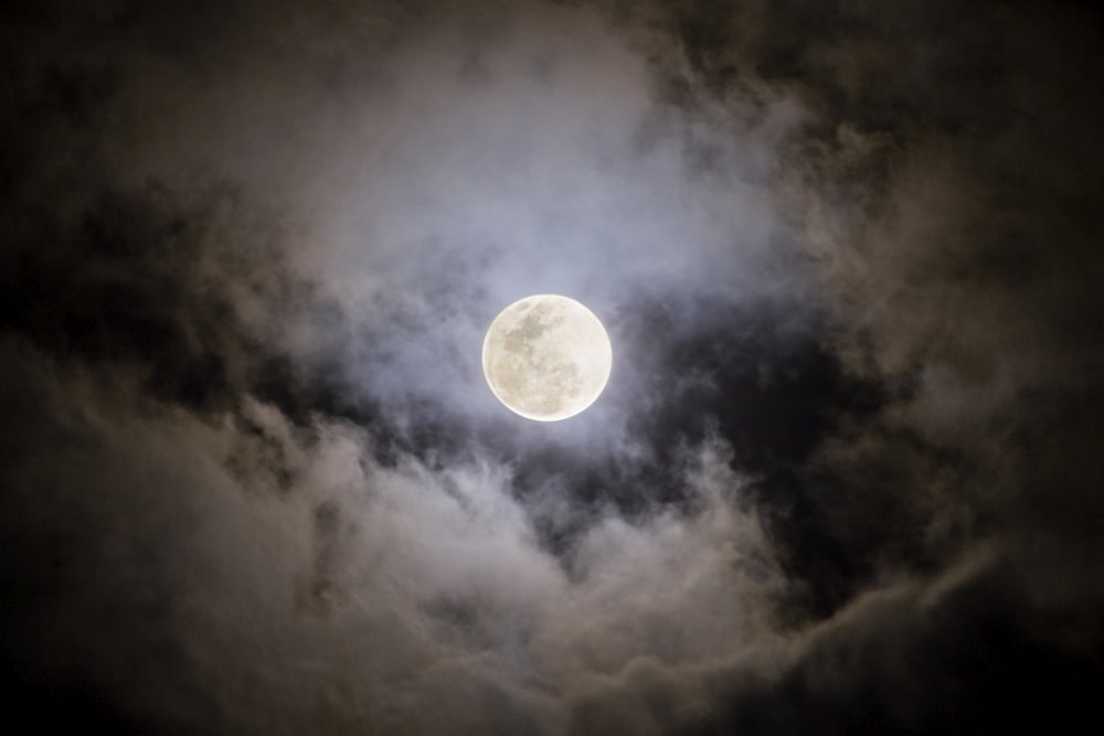 a full moon is seen through the clouds