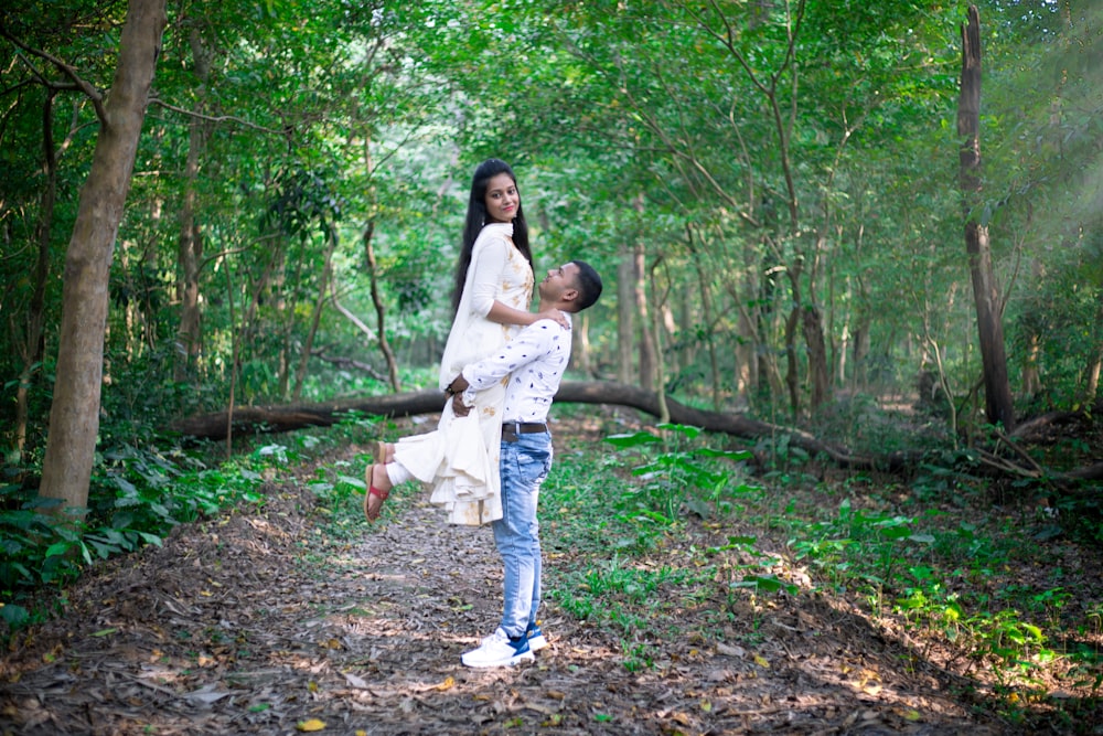 a man holding a woman in a forest