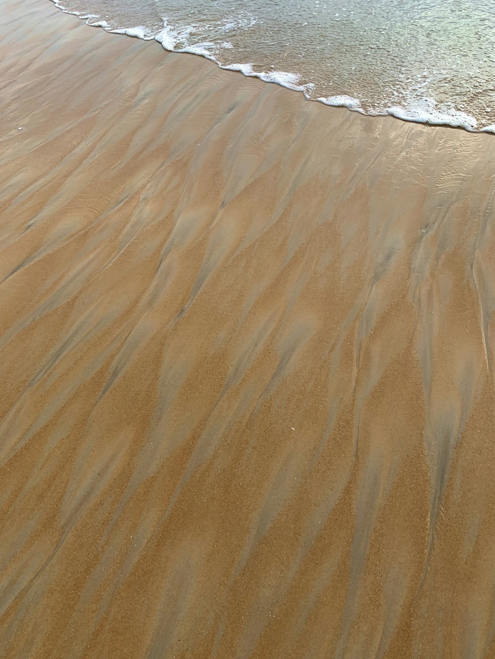 a sandy beach with waves coming in to shore