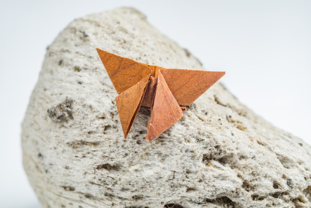 a brown origami butterfly sitting on a rock