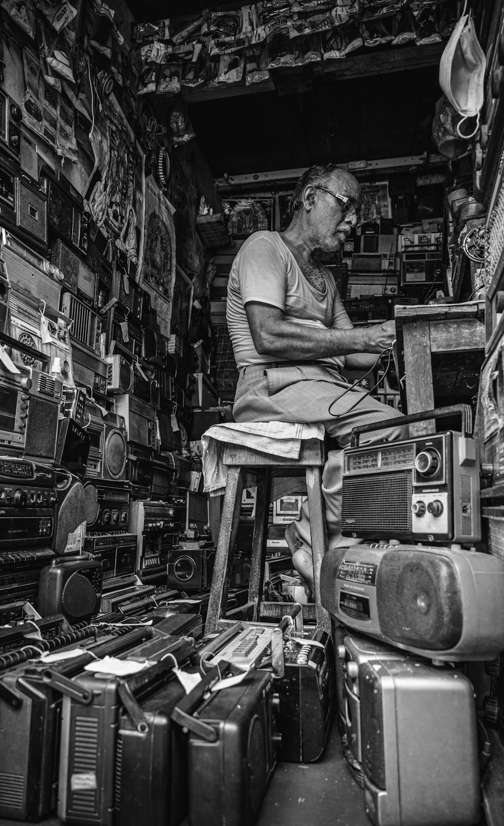 a man sitting on a stool in a room filled with electronics
