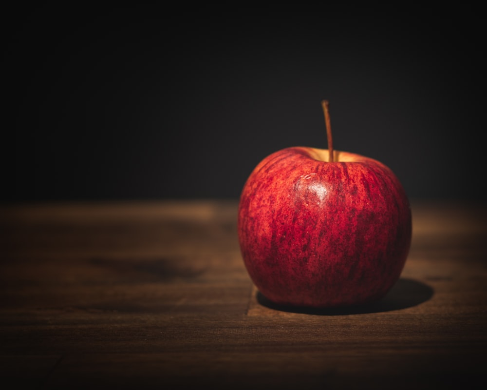 a red apple sitting on top of a wooden table