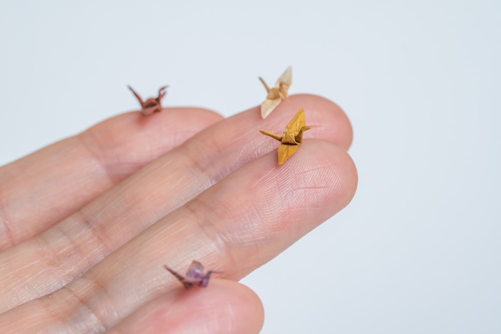 a person's hand holding three tiny origami birds