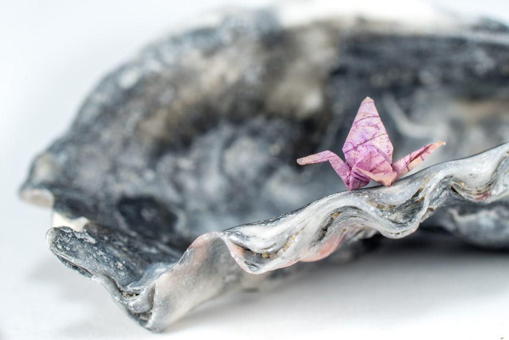 a pink origami origami sitting on a rock