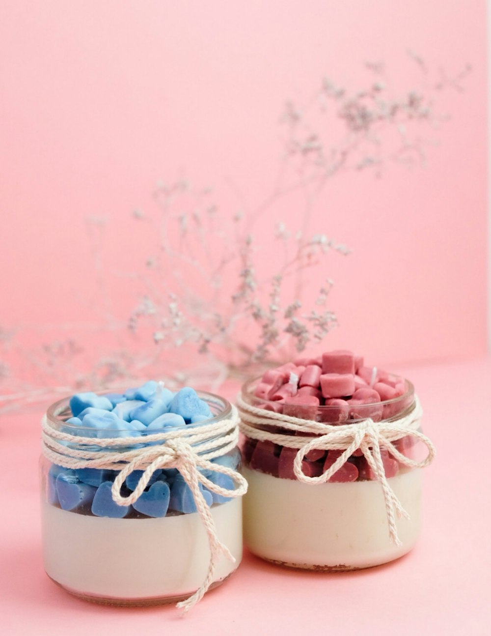two small jars filled with marshmallows on a pink surface