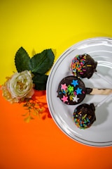 Close-up of elegant chocolate-dipped cake pops decorated with gold leaf accents.