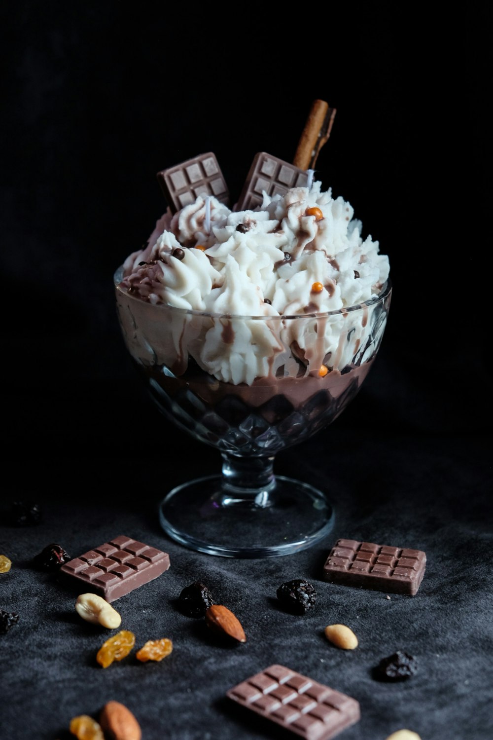 a dessert in a glass bowl with chocolate, nuts, and whipped cream