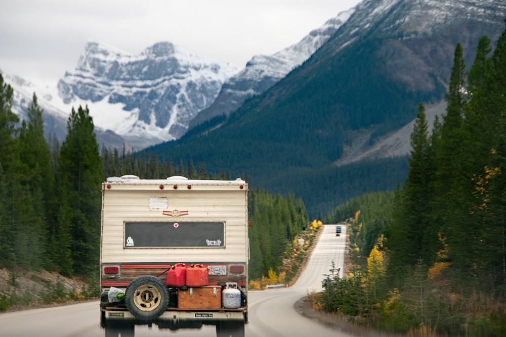 a truck driving down a road with mountains in the background