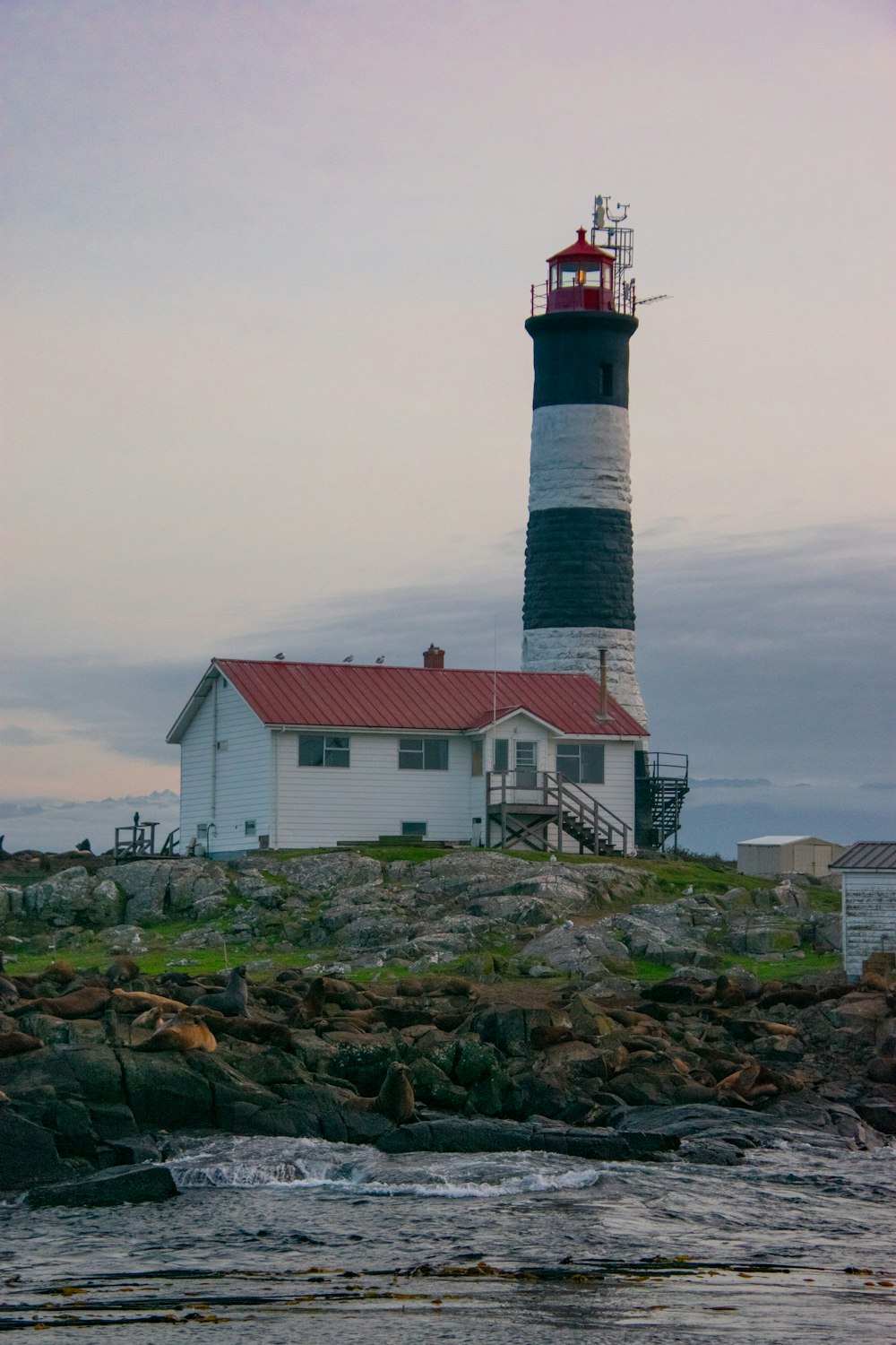 a lighthouse on a rocky shore with a red roof