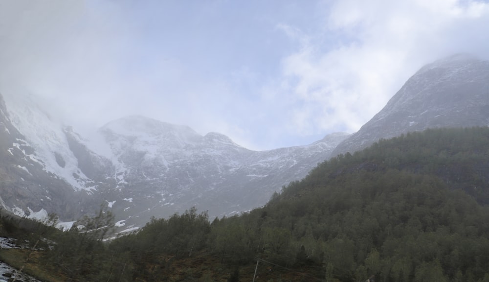 a mountain covered in snow and trees under a cloudy sky