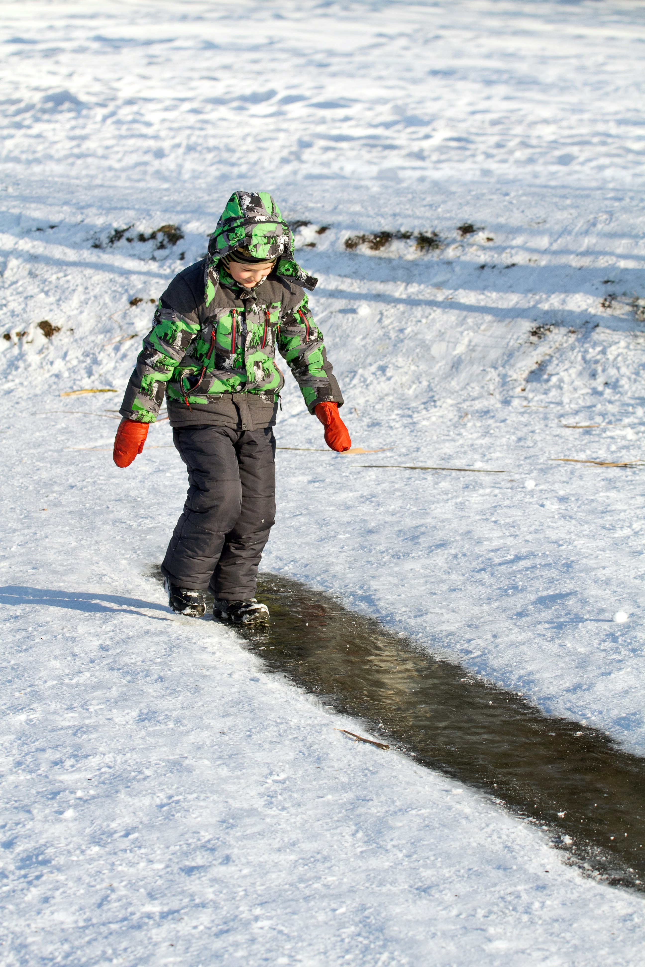 a young boy riding a snowboard down a snow covered slope