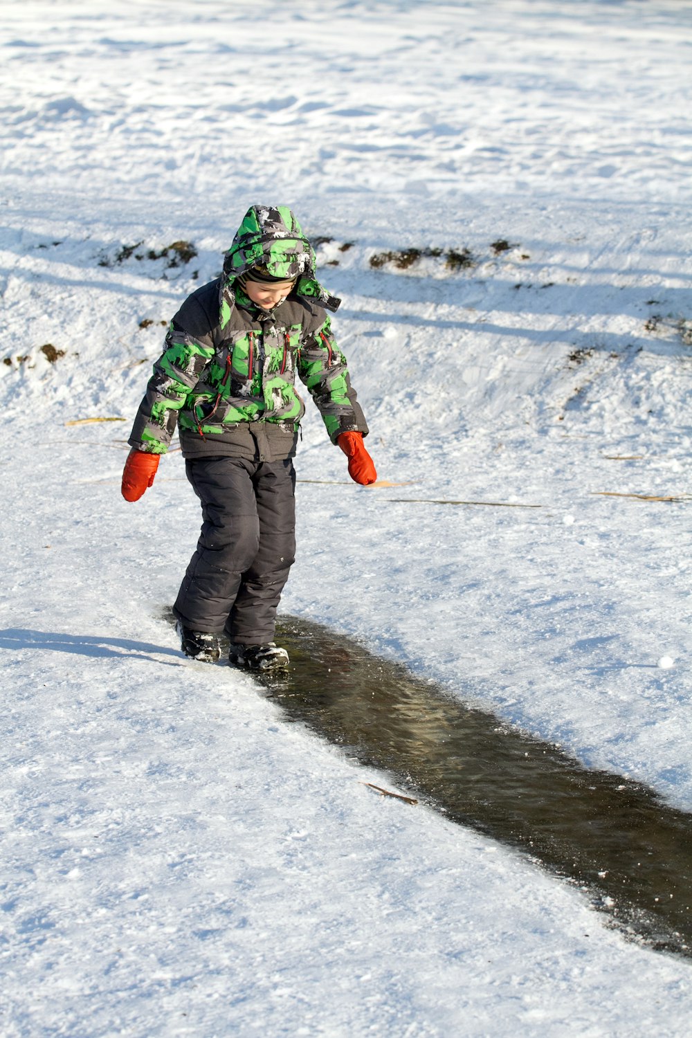 a young boy riding a snowboard down a snow covered slope