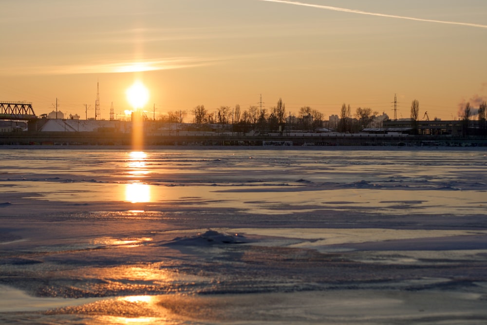 the sun is setting over a frozen lake