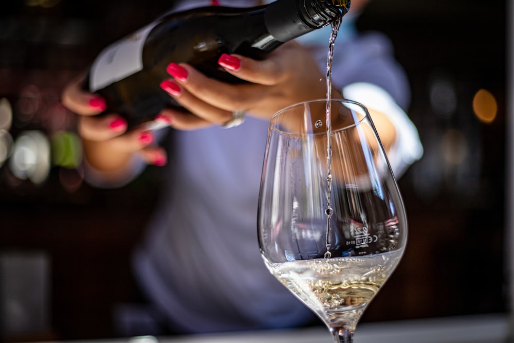 a woman pouring a glass of wine into a wine glass