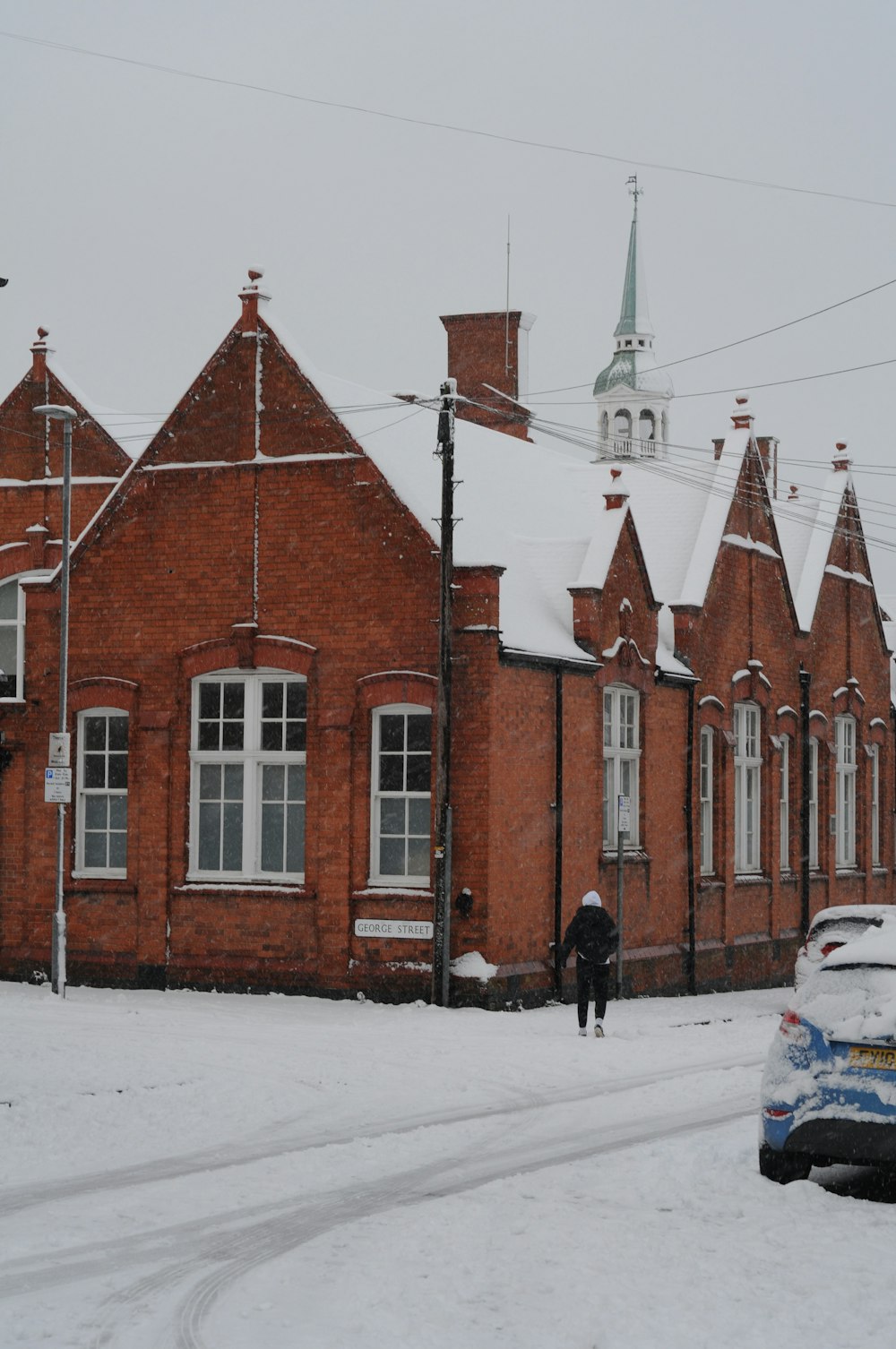 a car parked on a snowy street in front of a red brick building