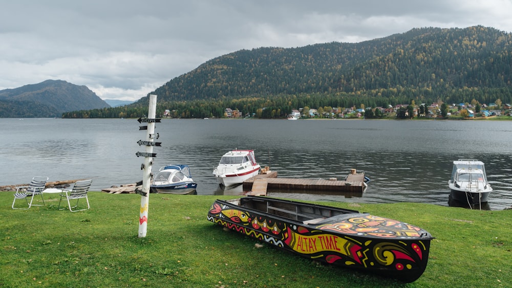 a boat sitting on top of a lush green field next to a lake