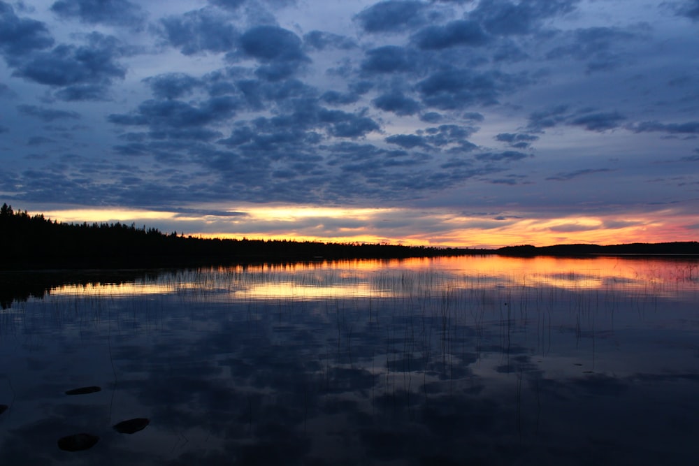 a body of water surrounded by trees and clouds