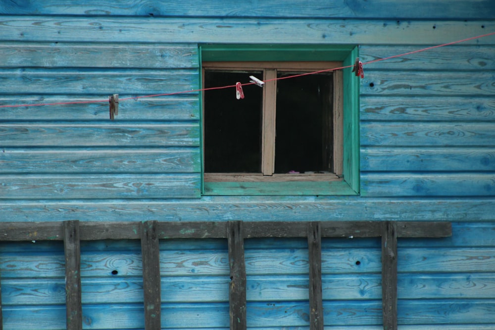 a blue building with a window and clothes line