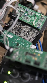 Several green circuit boards with various electronic components such as resistors, capacitors, and integrated circuits. Ribbon cables connect the boards, and blue cables are visible in the background.