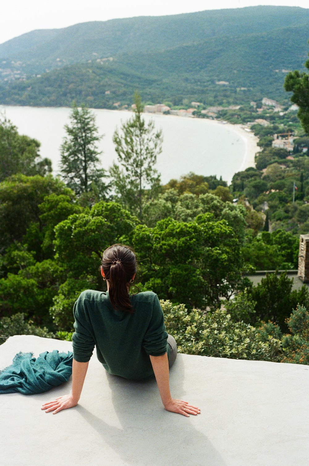 a woman sitting on a ledge looking at a lake