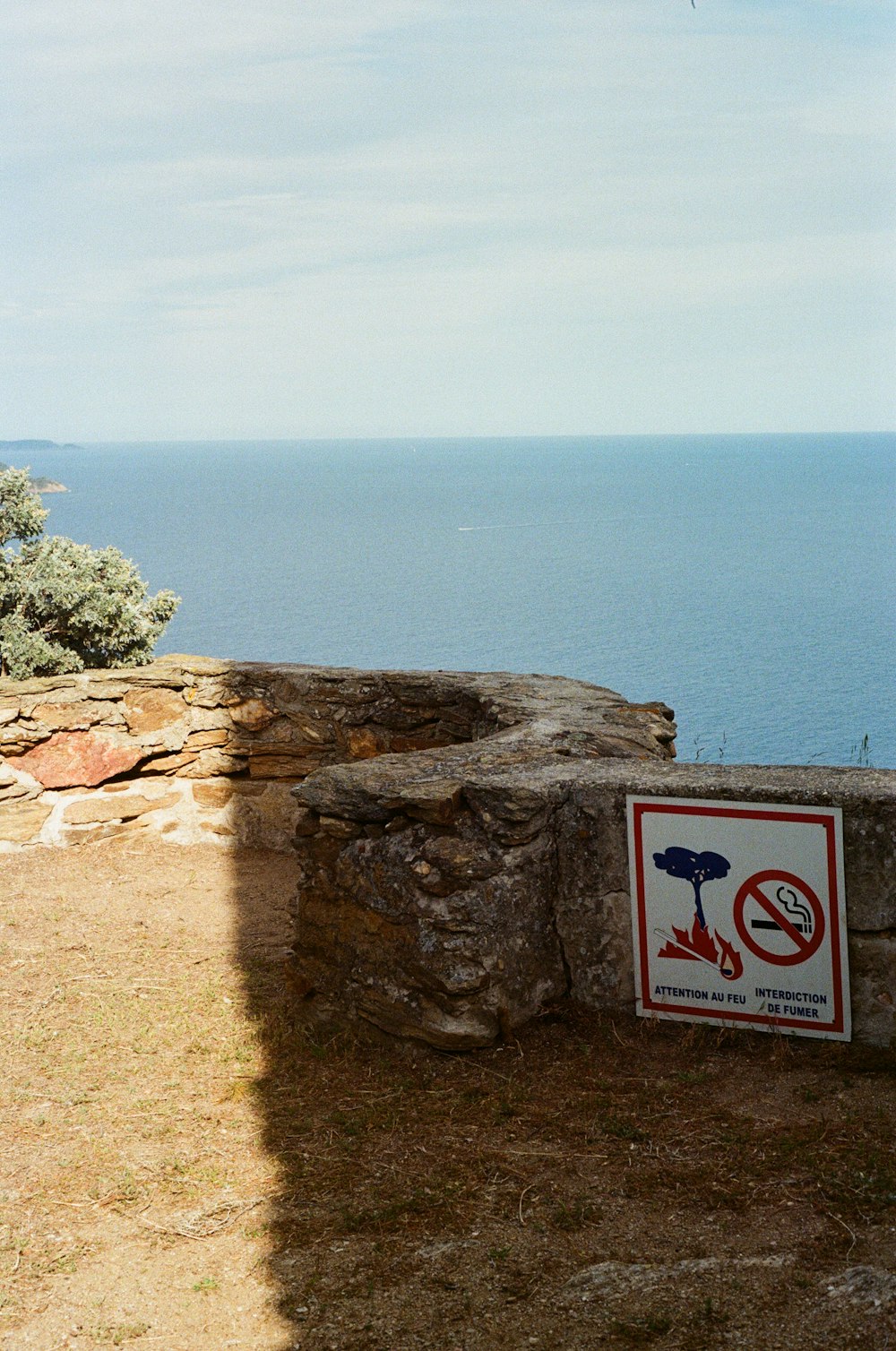 a sign on a stone wall near the ocean