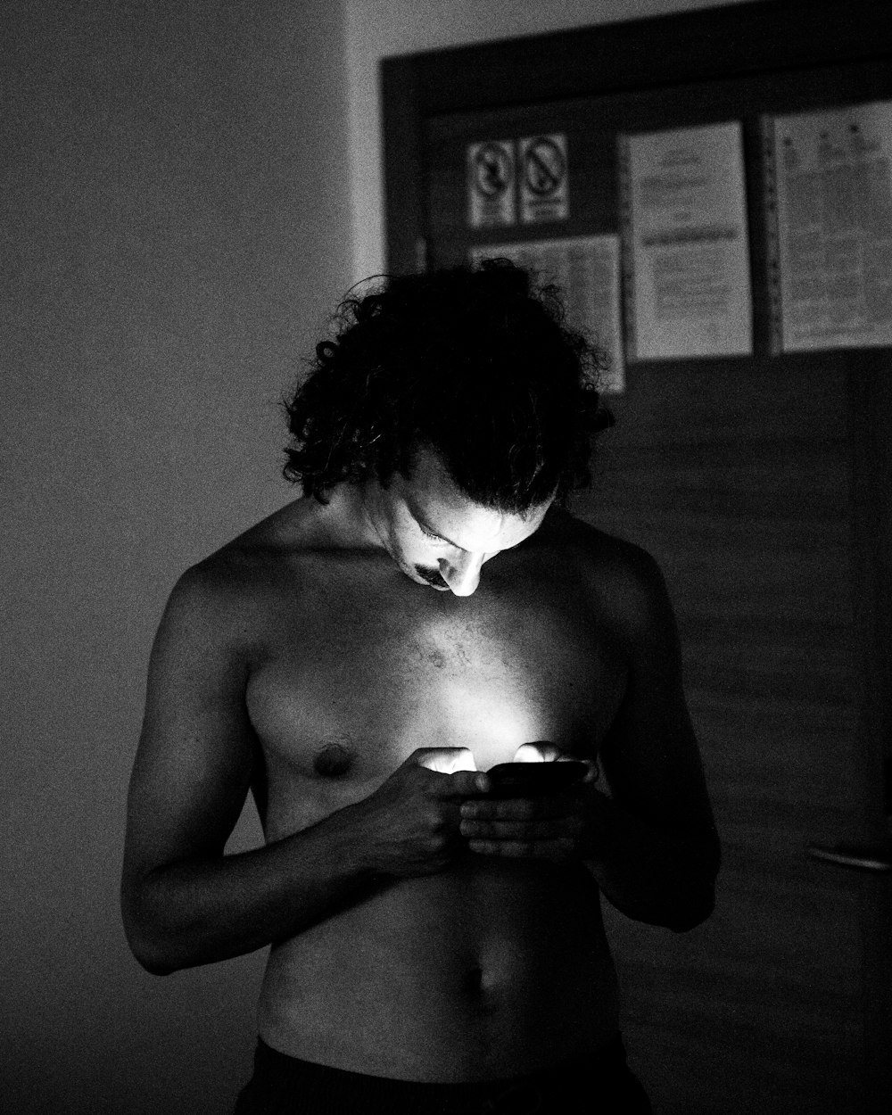 a shirtless man looking at his cell phone