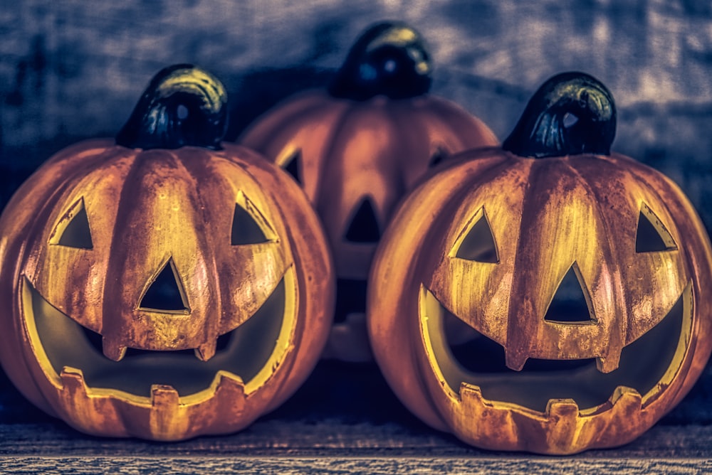 two carved pumpkins sitting on top of a wooden table