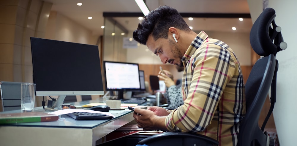 a man sitting at a desk using a cell phone