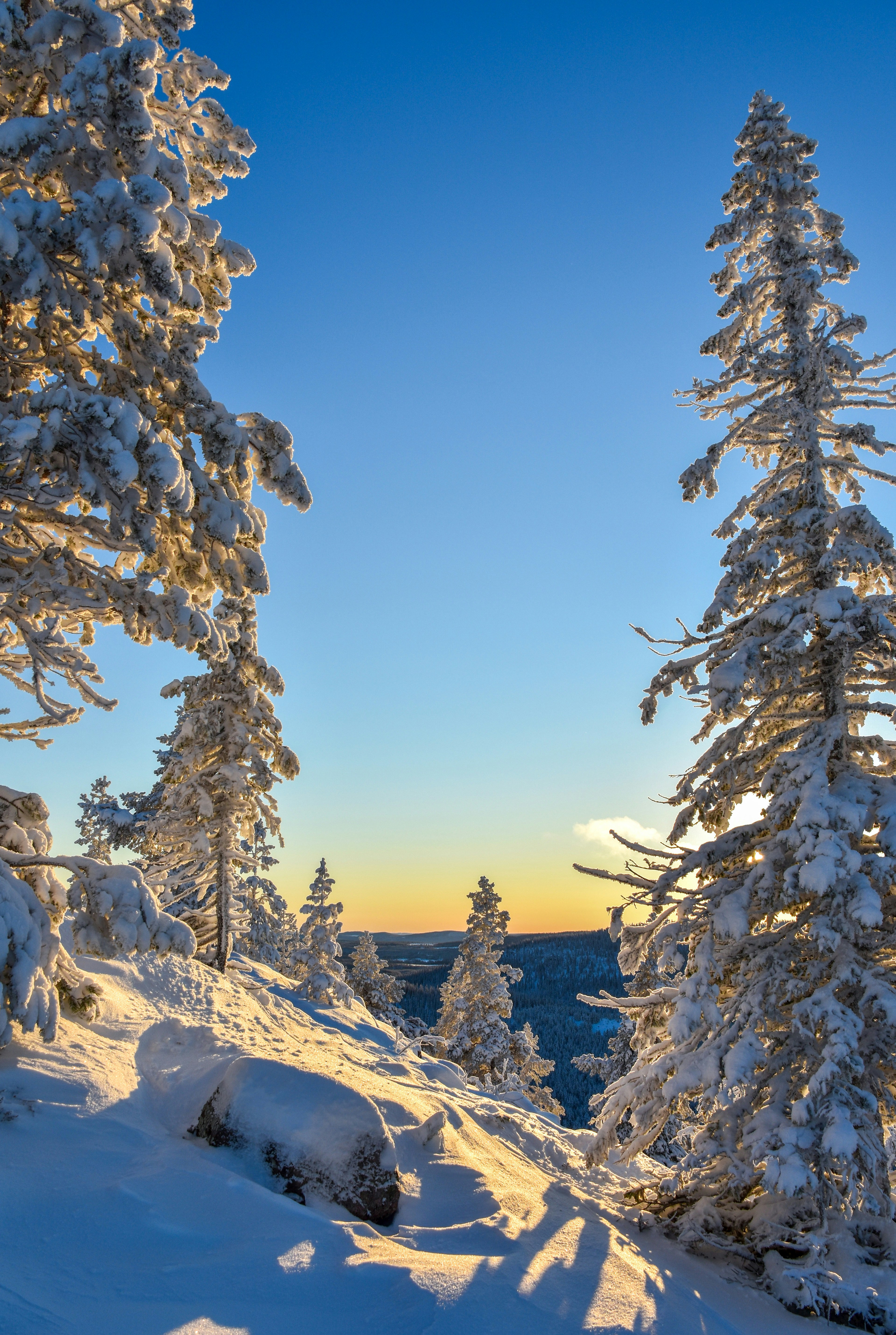 the sun is setting on a snowy mountain