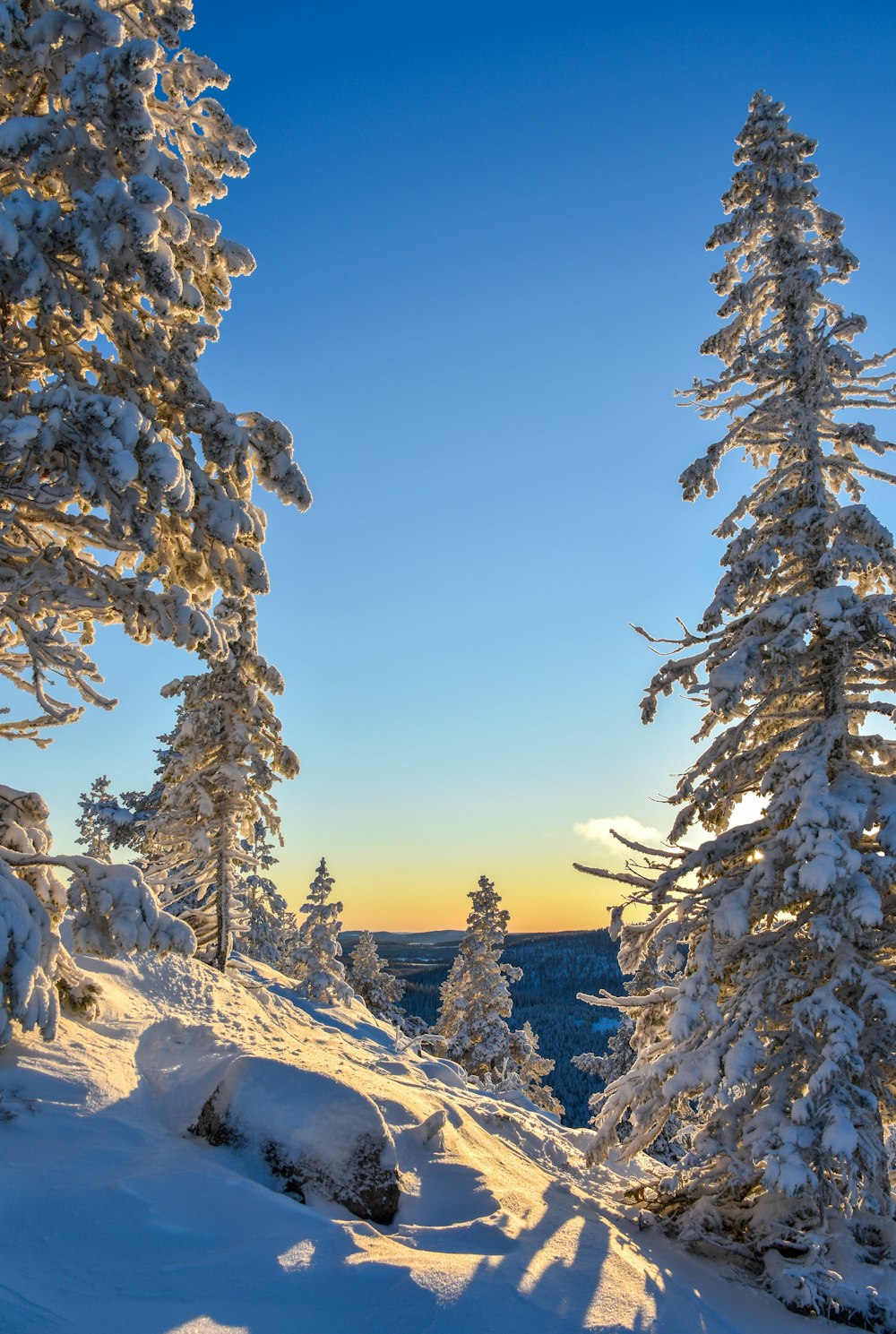 the sun is setting on a snowy mountain