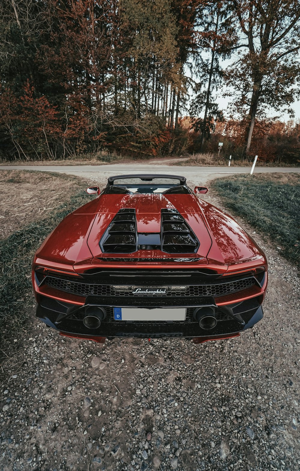 a red sports car parked on a gravel road