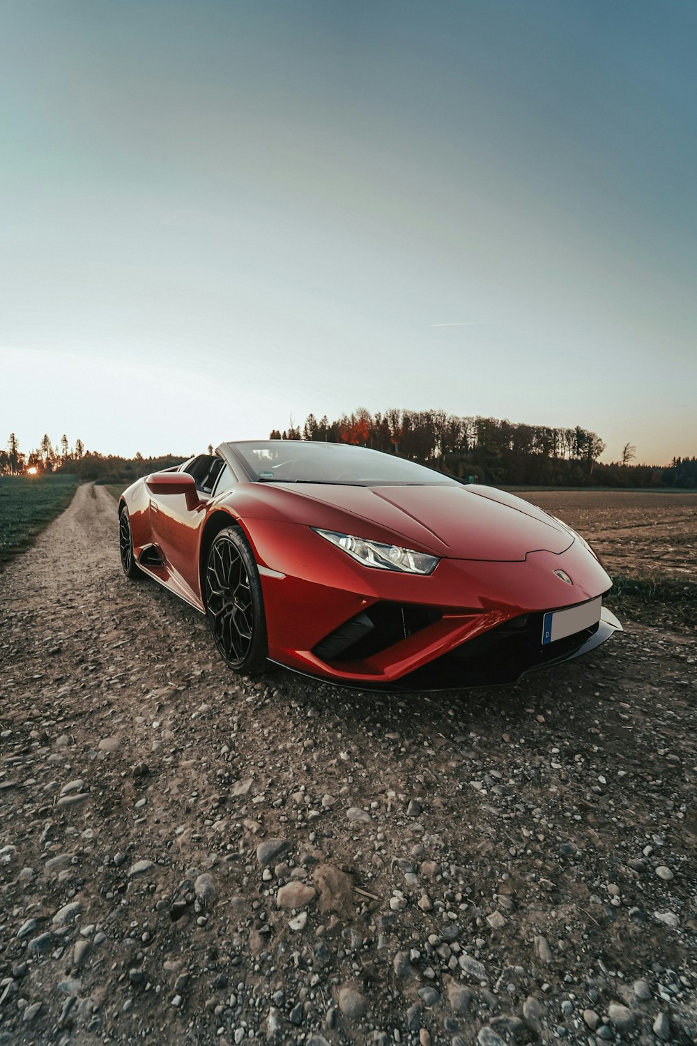 a red sports car parked on a gravel road