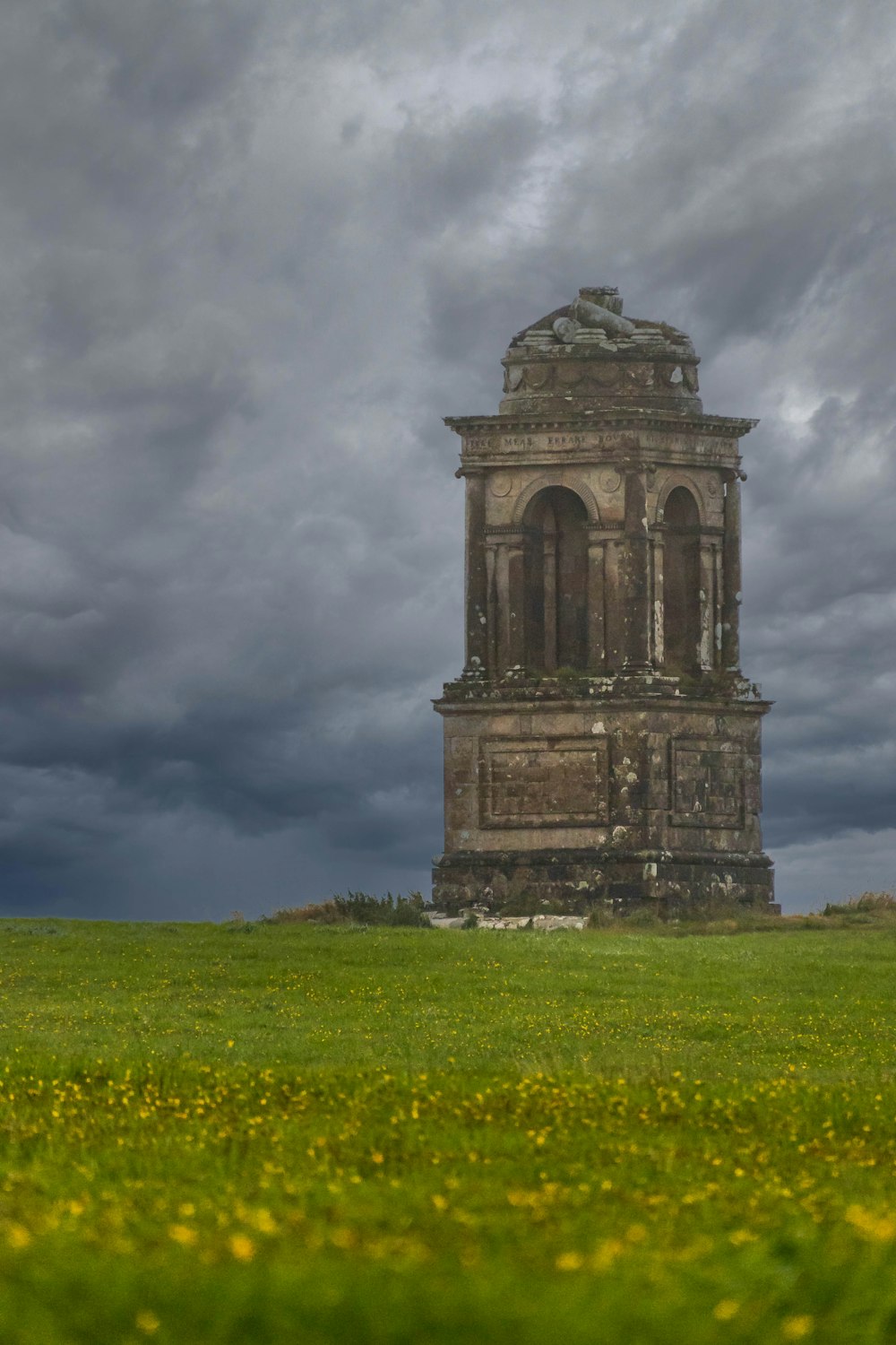 a tall tower sitting in the middle of a lush green field