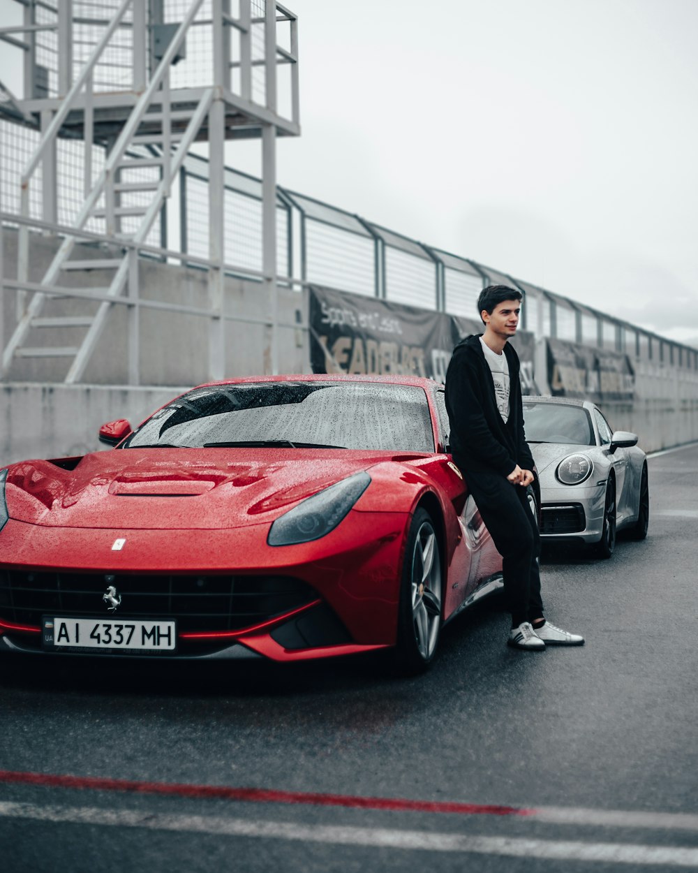 a man standing next to a red sports car