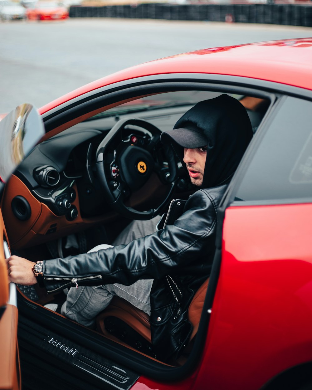 a man in a leather jacket sitting in a red car