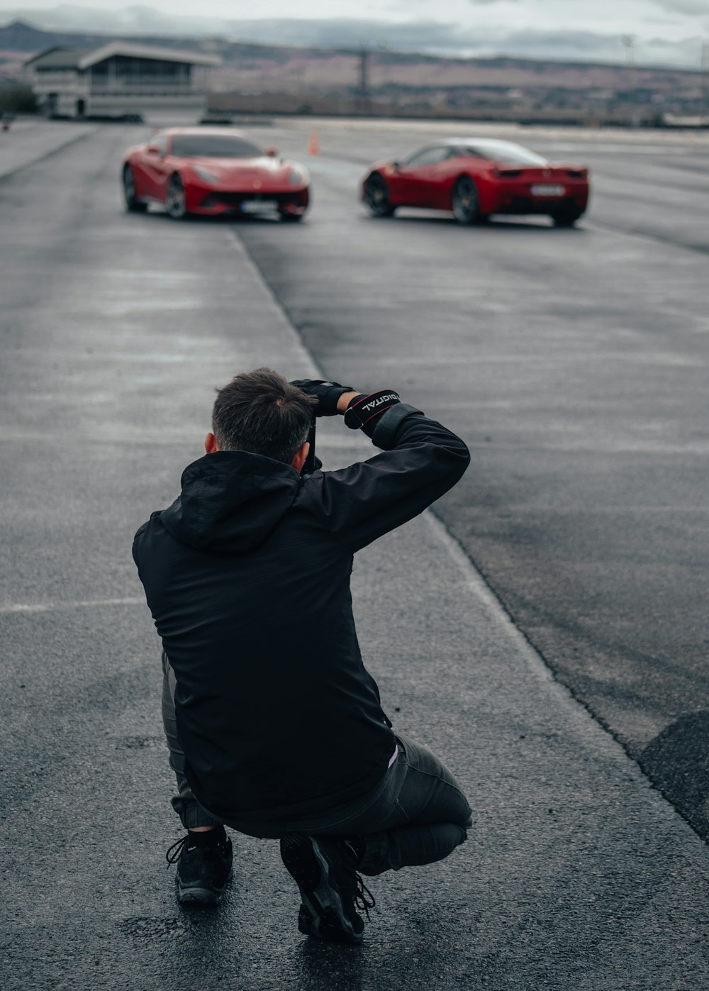 a man taking a picture of two red sports cars