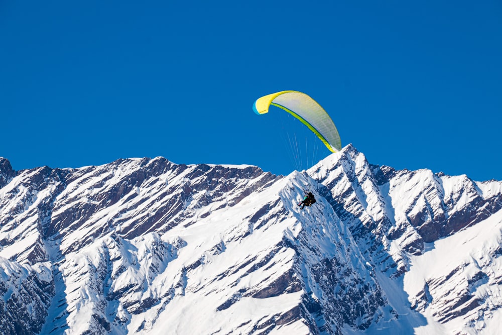 a person paragliding over a snow covered mountain