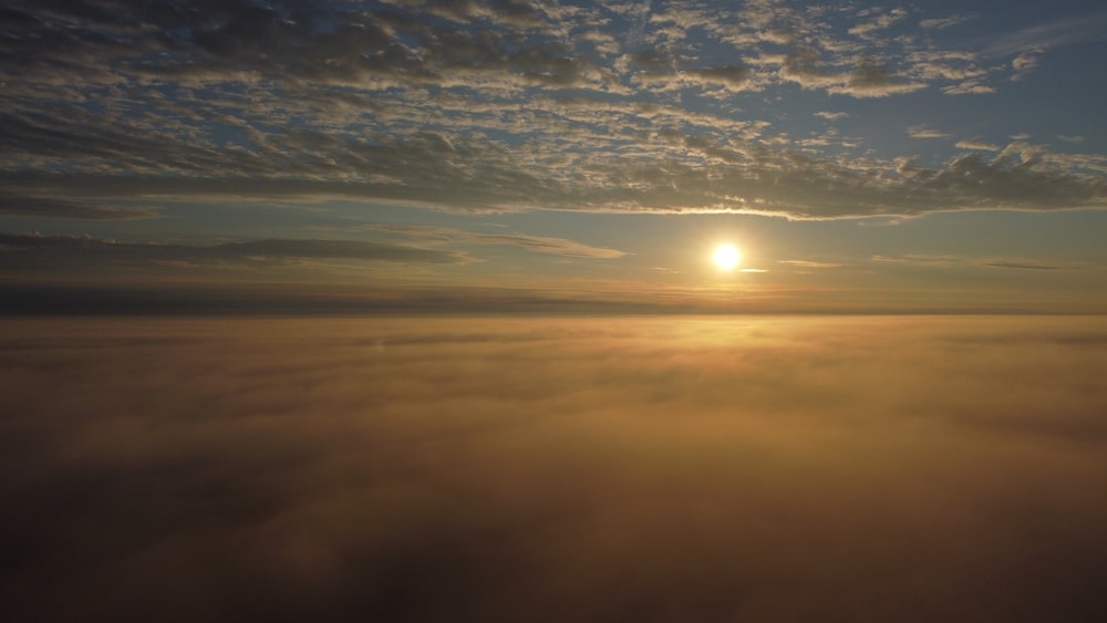 the sun is setting over the clouds in the sky