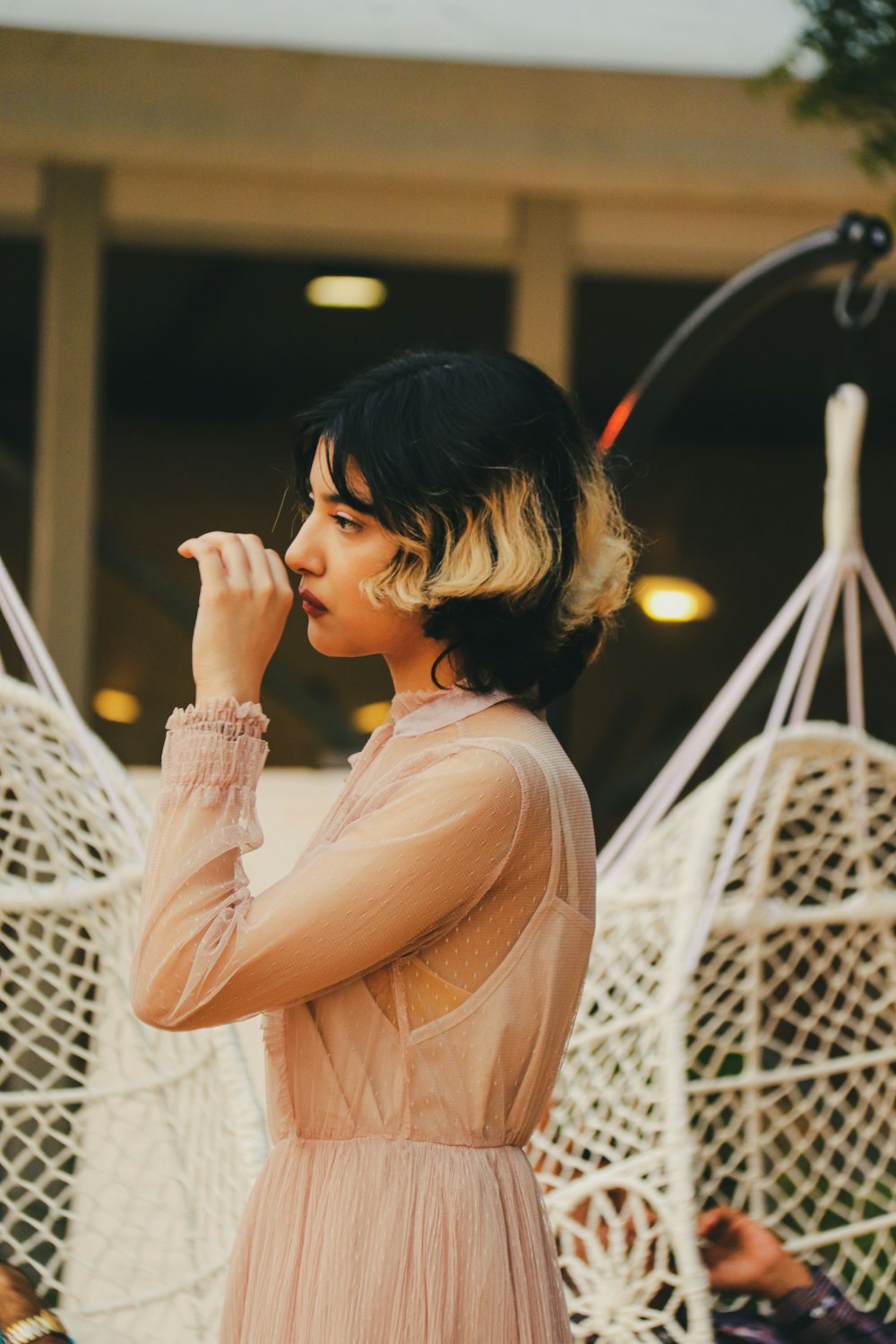 a woman in a pink dress standing in front of a hammock