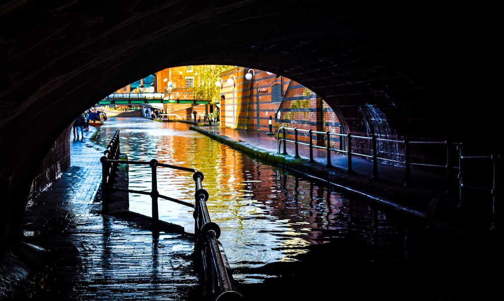 a dark tunnel leading to a street filled with water