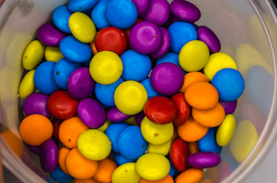 Close-up of colorful assorted candies in a rustic wooden bowl.
