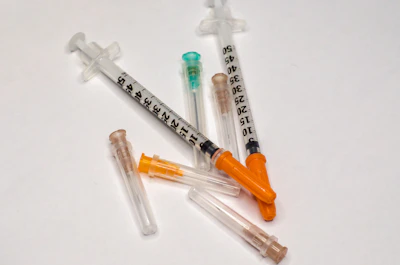 Sterile syringes and needles arranged neatly on a white surface