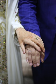 Close-up of a bride’s hands adorned with detailed henna designs, resting on a blush-colored silk fabric.
